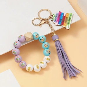 Detail view of teacher beaded keychain with purple tassel and engraved wooden plaque