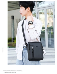 Scatto all'aperto di una borsa a tracolla nera in nylon da uomo con scomparti multipli a cerniera