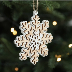 Detail of multi-layered wooden snowflake ornament hanging on a Christmas tree with warm lights