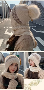 Detail of beige knitted winter hooded scarf with earflaps and soft faux fur pom-pom