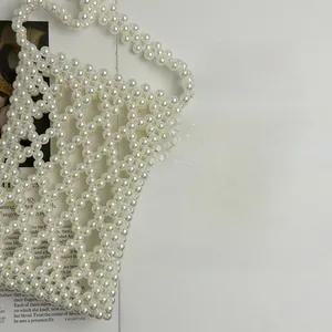 Detailed view of hand-woven white faux pearl lattice bag on a fashion magazine background
