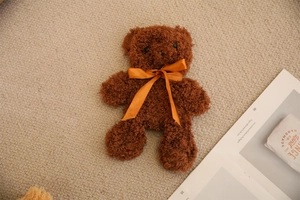 Detailed view of dark brown plush teddy bear skin with bright orange satin ribbon