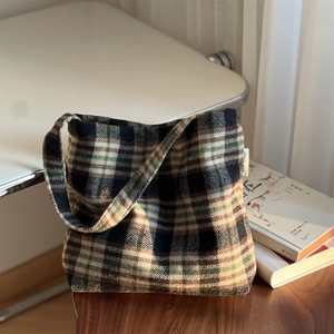 Détail du motif à carreaux en laine avec étiquette tissée sur un sac cabas vert