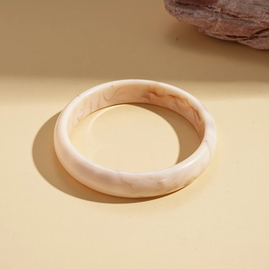 Detail of round resin bangle with ink texture on minimalist warm marble background