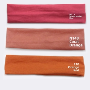 Detailed knit texture of three elastic cotton headbands in coral, orange and rose pink hues