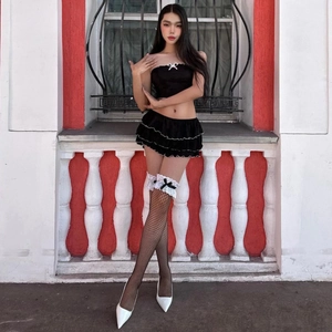 Détail d'une mini-jupe à volants et top bustier avec nœuds blancs et bas résille