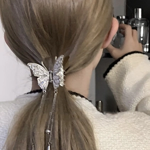 Silver butterfly hair claw clip with rhinestones and tassels shown on long hair