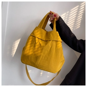 Close-up of yellow nylon tote bag showing textured fabric and wide shoulder strap
