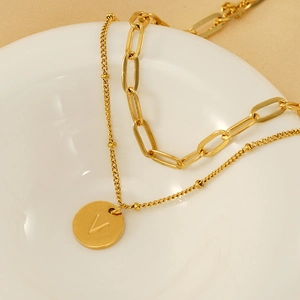 Detailed close-up of double-layer gold chain necklace with round V-letter pendant