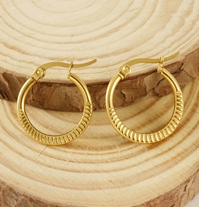 Close-up of golden stainless steel hoop earrings with textured grooved patterns