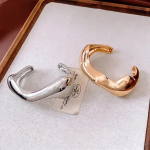 Irregular fluid-style open bangles in gold and silver finish with a polished mirror effect