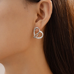 Close-up of heart-shaped hollow earrings in silver finish worn by a model