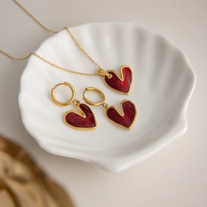 Dettaglio della collana a cuore e orecchini in smalto rosso su un vassoio decorativo
