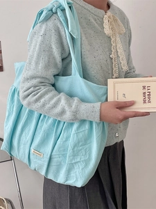 Light blue pleated canvas tote bag with bow shoulder strap for a minimalist style