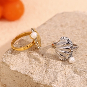 Elegant 18K gold and silver seashell rings with pearls and diamonds on natural stone