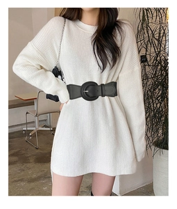 Detail of wide black elastic belt with oversized round buckle on white sweater