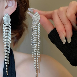 Close-up of dangling silver tassel earrings with shimmering rhinestones on ear