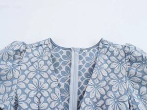 Detail von hellblauem Jacquard-Stoff mit unsichtbarem Reißverschluss und S-Etikett