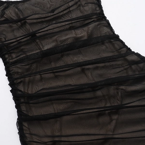 Detailed close-up of ruched black mesh fabric texture on an elegant bodycon dress