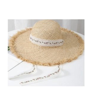 Détail d'un chapeau de soleil en raphia avec bords effilochés et ruban de dentelle