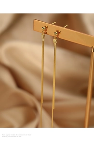 Macro shot of gold long tassel earrings on a display stand with silk background