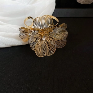 Macro detail of golden metal hollow flower napkin ring with sparkling crystal center