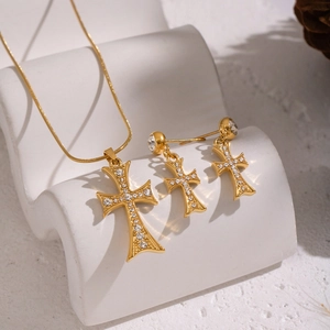 Parure collier et boucles d'oreilles croix dorée avec zircons sur présentoir blanc