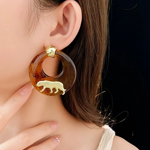 Detail of tortoiseshell hoop earring featuring a gold-tone leopard accent on model