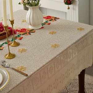 Detail of Christmas tablecloth with lace edges and festive bell embroidery on a dining table