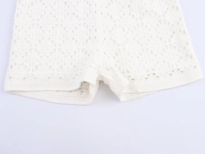 Detail shot of white crochet lace knit fabric with intricate hollow embroidery patterns