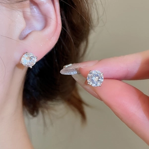 Macro shot of silver stud earrings with sparkling round cubic zirconia on a model ear