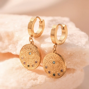 Bohemian gold plated evil eye drop earrings with colorful crystals on stone surface
