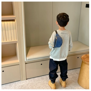 Kids blue denim crossbody bag shown on child model in a modern indoor setting