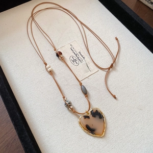Detail of vintage heart pendant necklace with tiger eye stone and wood beads on rope