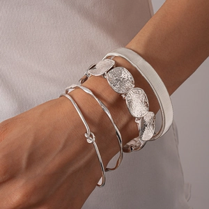 Detailed close-up of four-piece silver geometric textured bracelets worn on a wrist