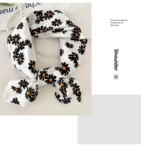 Detail of white cotton linen scarf with black daisy print and elegant pearl necklace