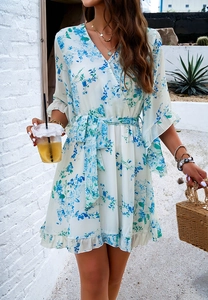 Detail of V-neck white chiffon dress with blue floral print and ruffled mid-length sleeves