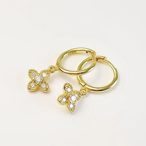 Macro detail of gold S925 sterling silver hoop earrings with zircon flower charms