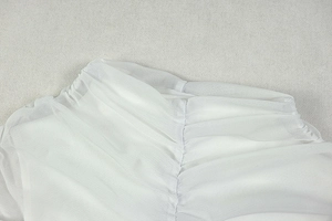 Detail of white mesh dress showing delicate ruched texture and translucent fabric