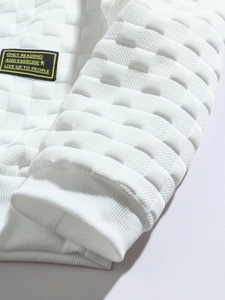 Detail of white waffle knit fabric texture and sleeve cuff with decorative text label