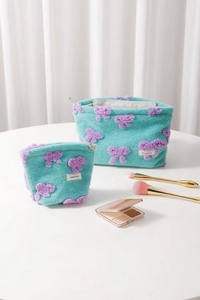 Detail of plush mint green makeup bags with purple bear patterns and metal zipper closure