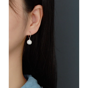 Close-up of a silver S925 sterling silver hoop earring with an engraved round pendant