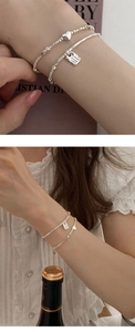 Detail of 925 sterling silver layered bracelets with heart charm and square letter tag