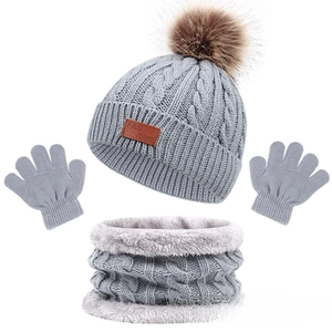 Detailed view of kids grey knit hat with fur pompom, matching scarf, and mittens set