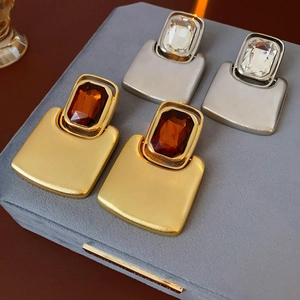 Detailed close-up of rectangular crystal earrings in gold and silver metal frames