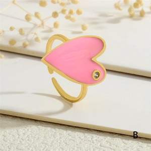Close-up of golden adjustable ring with pink heart and small clear gemstone detail