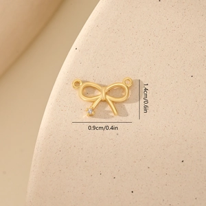 Detail of gold bow charm with white zircon and size measurements 0.9cm by 1.4cm