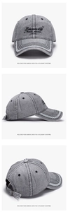 Detail of grey washed denim baseball cap featuring black embroidery and white lace brim