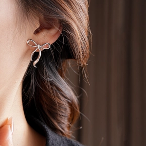 Gros plan de boucles d'oreilles nœud en argent montrant un éclat métallique élégant