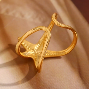 Gros plan détaillé d'une bague étoile de mer dorée sur un élégant tissu en satin brun